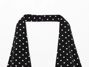 Close-up of white polka dot pattern on black fabric with delicate neck strap detail
