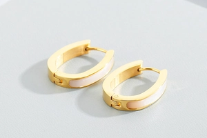 Detailed close-up of gold oval hoop earrings with elegant white shell inlay details
