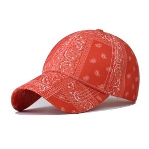 Close-up of red baseball cap featuring white paisley print and detailed cotton stitching