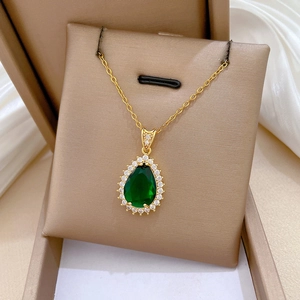 Macro detail of teardrop green zircon pendant with halo setting on gold necklace