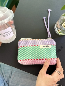 Colorful striped knit cosmetic pouch with purple zipper and woven textured handle strap