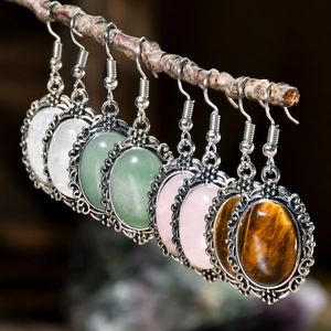 Retro hollowed silver earrings featuring oval crystals hanging on natural branches