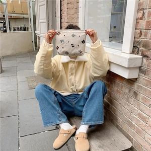 Detailed embroidery of cat heads on a beige cotton canvas pouch held in a lifestyle setting