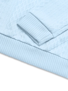 Detail of light blue knit top featuring diamond texture and ribbed cuff construction