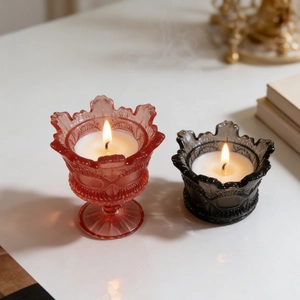 Pink and charcoal crown shaped relief glass candle jars with warm glowing flames