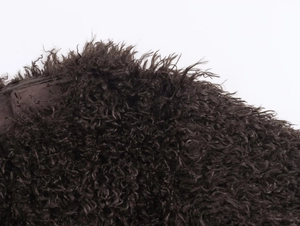 Macro shot of dark brown curly faux fur material showing the plush and fluffy texture