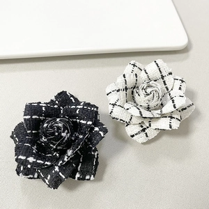 Detail of black and white houndstooth fabric camellia brooches on light background