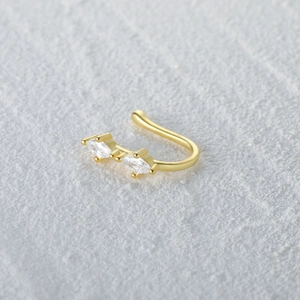 Macro shot of gold S925 sterling silver U-shaped nose cuff with marquise-cut zircons