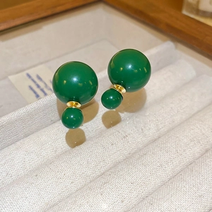 Macro shot of forest green double bead earrings with golden metal studs on a tray
