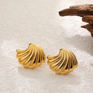 Detail of gold shell earrings with polished metallic texture and pleated shell design