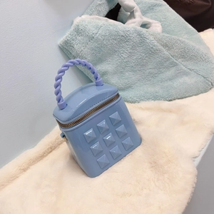 Close-up of sky blue mini bucket bag with twisted handle and golden zipper on plush surface