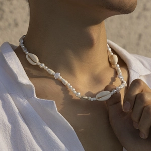Men's hip hop necklace with white shell and pearl beads worn by a model in nature