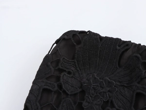 Dettaglio ravvicinato della trama di pizzo nero e dei ricami floreali sul capo d'abbigliamento
