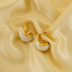 Detail of gold-plated water drop earrings with marble resin texture on silk background