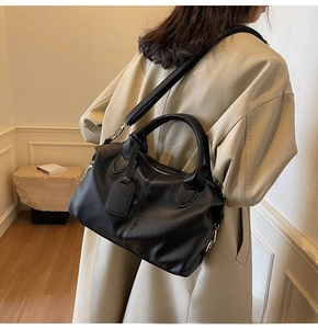 Close-up of black lychee grain leather tote bag with dual handles and crossbody strap detail