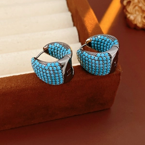 Detail of broad C-shaped hoop earring with blue beads on a gun-black metal base