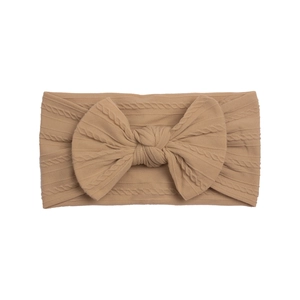 Detail showing the cable knit texture and large bow on a wide nylon baby headband