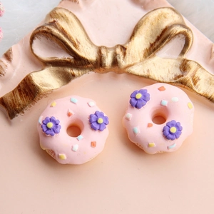 Nahaufnahme von rosa Harz-Donut-Anhängern mit bunten Streuseln und lila Blumendetails