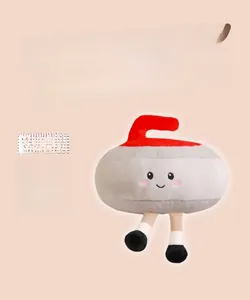 Détail de la peluche en forme de pierre de curling avec poignée rouge et visage brodé