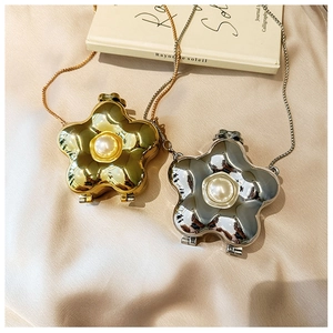 Detail of gold and silver flower-shaped mini bags with central pearl and metal chain