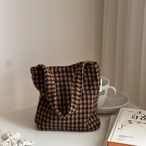 Detailed view of vintage houndstooth tweed handbag styled on a white desk