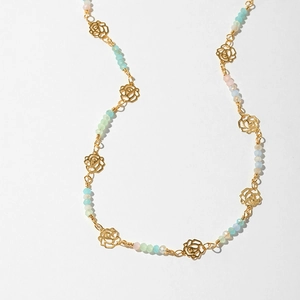 Detail of bohemian necklace with golden metal roses and pastel frosted beads
