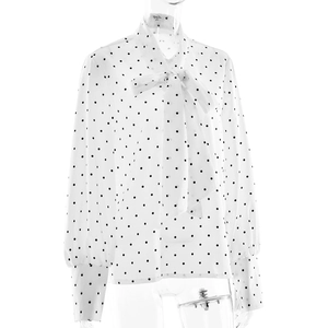 Détail de la blouse blanche à pois avec encolure élégante à nœud papillon et manches longues