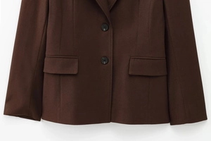 Detail view of dark brown blazer featuring double button closure and flap pockets