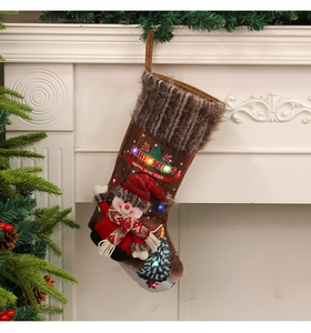 Lighted Christmas stocking with snowman doll and plush cuff hanging on white fireplace