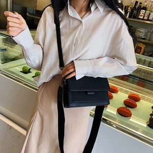 Minimalist black PU leather flap crossbody bag with a wide strap on a female model