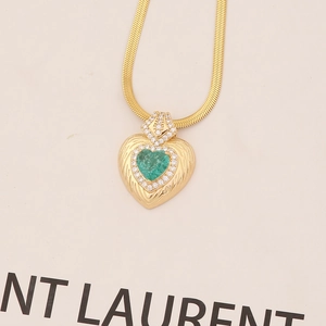 Flat gold snake chain necklace with a green gemstone heart pendant and crystal accents