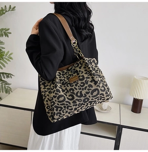 Detail of leopard print tote bag with brown leather strap and chain on a stylish model