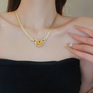 Detailed view of a vintage oval yellow gemstone necklace with diamonds on a flat snake chain