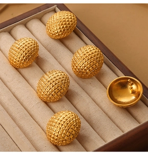 Macro detail of vintage gold-plated titanium steel earrings with diamond-pattern texture