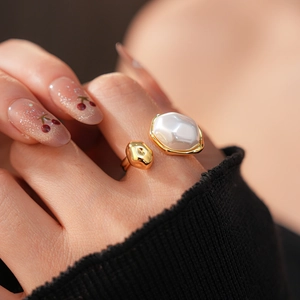 Gros plan d'une bague ajustable plaquée or avec une perle ovale blanche sur un doigt