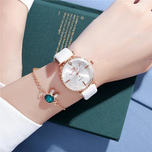 Close-up of rose gold watch with white leather strap and emerald rabbit bracelet