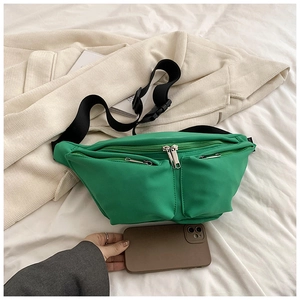 Detail view of bright green nylon crossbody bag with multiple zipper pockets and adjustable strap