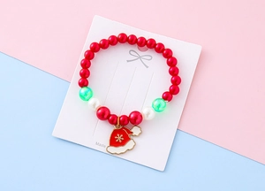 Close-up of a Christmas beaded bracelet with red pearls and a festive Santa hat charm