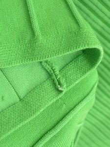 Detailed macro shot of green knit fabric texture and seam craftsmanship on dress