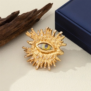 Spilla occhio dorata vintage con raggi di sole e cristalli su superficie strutturata