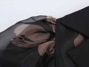 Détail du col tailleur et manches bouffantes transparentes à imprimé abstrait noir