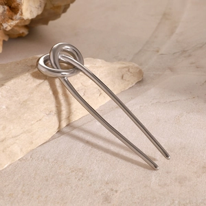 Close-up of silver stainless steel knot hair pin resting on a textured natural stone