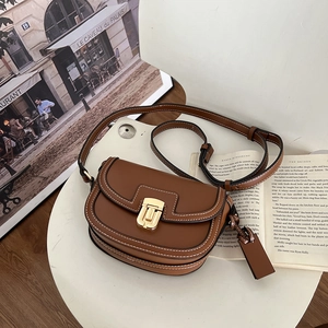 Dettaglio borsa a sella in pelle marrone con chiusura dorata e cuciture a contrasto