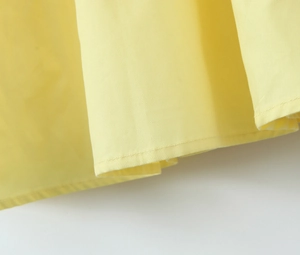 Gros plan sur la texture du tissu jaune et les détails de couture de l'ourlet