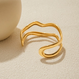 Minimalist 18K gold stainless steel double-layer wave open bangle on a textured surface