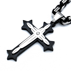 Gros plan du pendentif croix multicouche argent et noir orné d'une pierre précieuse