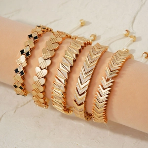 Set of five elegant gold bracelets with clover, heart, and V-shapes with zircon accents