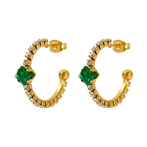 Detailed shot of vintage C-shape gold earrings with emerald gem and pavé zircon stones