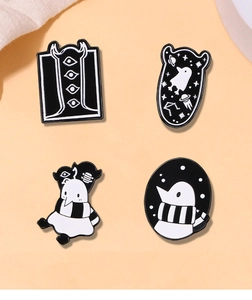 Detailed view of four black and white enamel pins with creative alien and ghost designs