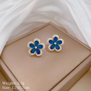 Close-up of blue five-leaf flower earrings with gold plating and teardrop crystals
